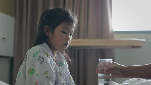 Mother giving a glass of water to her sick daughter