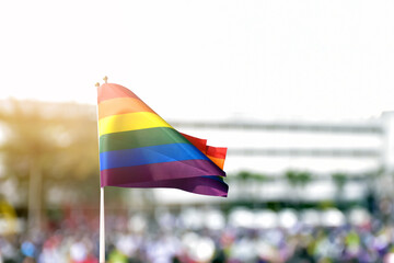 Rainbow flag, a symbol for the LGBT community, waving in the wind with blur asian students in the morning activities background. concept for supporting and campaigning the lgbtq+ communities at school