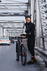 Fototapeta na wymiar Cyclist with his bike smiling at steel bridge