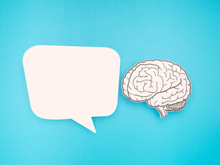 White speech bubble and a brain shape made from paper on a blue background