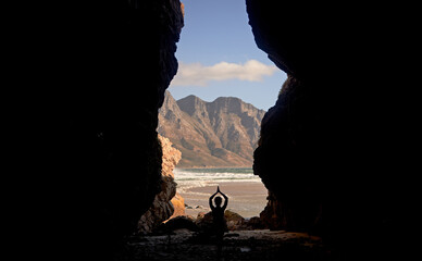 Yoga opens the mind to beautiful things. Shot of a woman practising yoga while sitting in a cave overlooking the sea.