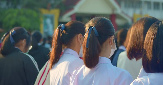 Slow motion scene in the morning while the Asian high school students in white uniform wearing the masks stand in line during the Coronavirus 2019 (Covid-19) epidemic.