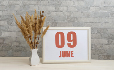 june 9. 9th day of month, calendar date.  White vase with ikebana and photo frame with numbers on...