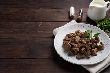 Fried or baked chicken liver with onion and sauce, green parsley leaves on a plate. Meat dish enriched with iron. copy space