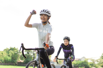 excited young woman riding her road bike with friend