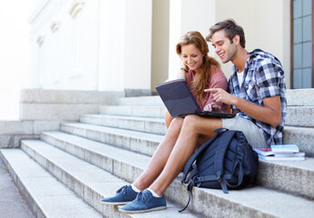 Now it makes more sense. Male and female student on the steps of their university sharing some study advice.