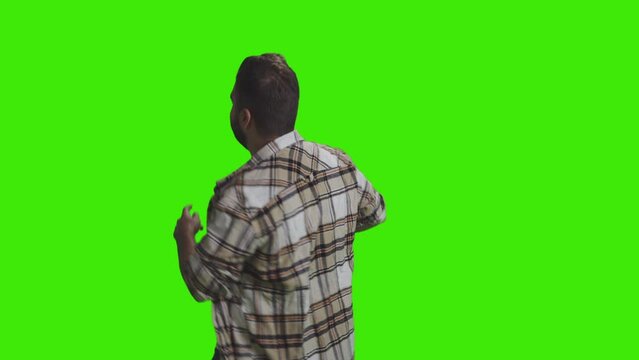 A young smiling boy is dancing and clapping in club facing the opposite direction on greenscreen