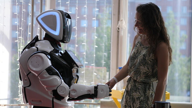 A cyborg and a young woman are cooperating each other are touching hands