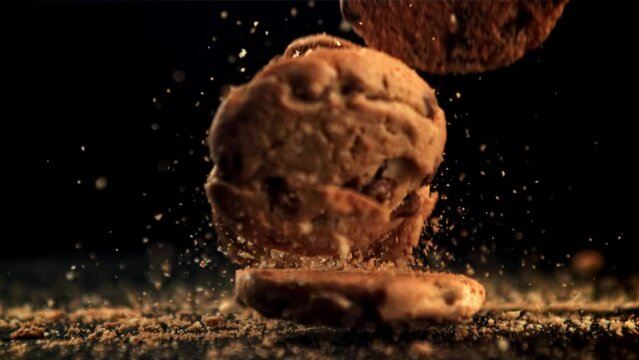 Cookies with pieces of chocolate fall on the table and crumble. On a black background. Filmed is slow motion 1000 fps.High quality FullHD footage