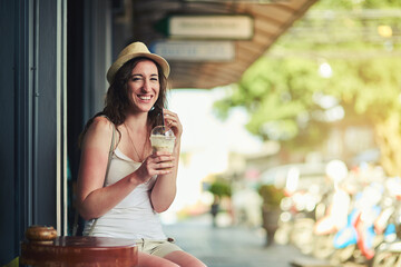 She knows where to go for a caffeine kick. Portrait of a young woman enjoying a chilled coffee beverage while on vacation.