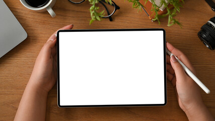 Working table or study table with female hand holding a digital tablet