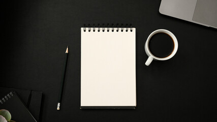 Modern dark and black office desk background with empty notepad