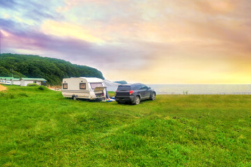 Mobile home, tent and car at sunset. Tourist camp by the sea, lake. Trailer