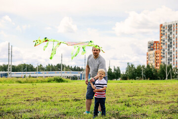 Happy family in summer park. Father and son child with flying kite