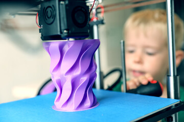 Toddler, a child with a screwdriver is studying 3D printing. Part growing, prototyping.