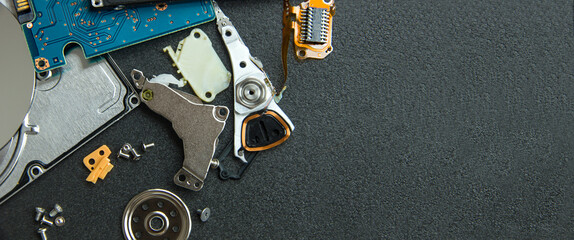 Broken damaged hard disk with scattered components showing loose disks and printed circuit board with unfolded mounting hardware