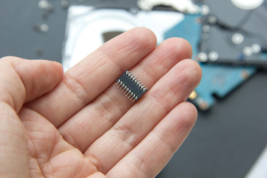 Hand holds chip compenent. Embedding the chip under human skin, microcontroller implanting NFC technology