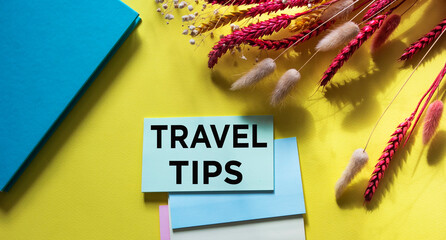 On a yellow background is a notepad, wheat and a sticker with the word TRAVEL TIPS. Travel concept