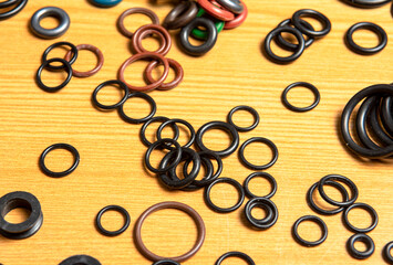 Black hydraulic and pneumatic o-rings in different sizes on a wooden background. Sealing rings for hydraulic connections. Rubber seals for plumbing.