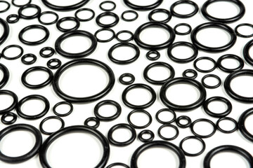 Hydraulic and pneumatic o-rings in black in different sizes on a white background. Various seals for plumbing. abstract background