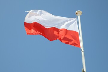 poland flag white red on mat in the wind and blue sky