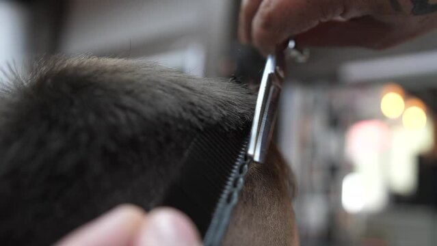 The master makes a cut with scissors and and a comb client to a man in a barber shop. slow motion