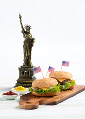 Studio shot two cheeseburgers on cutting board with small United States of America national flag...