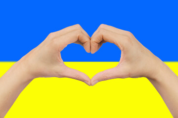 Fototapeta premium female hands in the shape of a heart on the background of the Ukrainian flag.