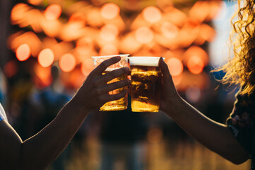 Hands of friends holding beer and toasting on a music festival