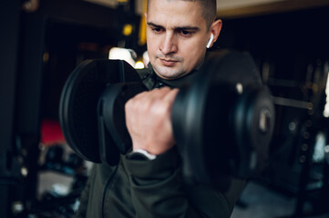 Fototapeta na wymiar Man training in the gym and lifting dumbbells