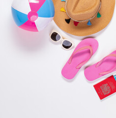Top view shot of handicraft hat, sunglasses, colorful ball with pink slipper sandal for summer beach sea travel vacation on white background