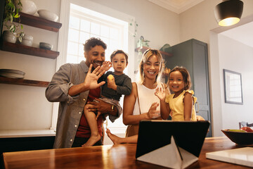 Diverse family waving during a video call at home