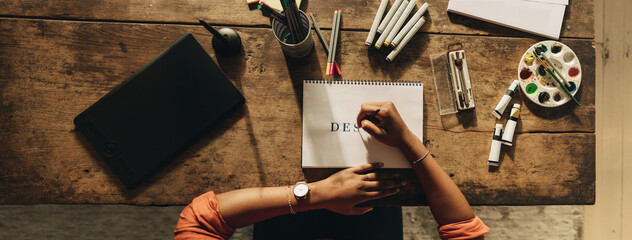 Black female designer drawing on a note pad - obrazy, fototapety, plakaty