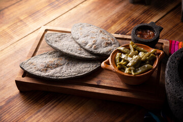 Tlacoyos and Nopales. Mexican pre hispanic dish made of blue corn flour patty filled with refried beans. Popular street food in Mexico.
