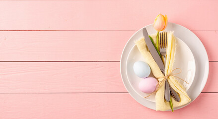 Table setting for Easter feast. Easter eggs, tulips and cutlery top view flat lay on pink rustic background