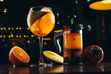 Aperol spritz and mango tea in french press on dark wooden background