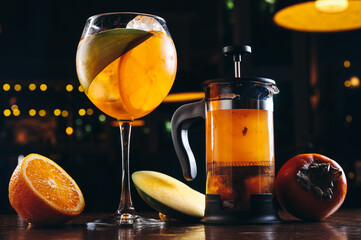 Aperol spritz and mango tea in french press on dark wooden background