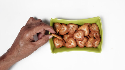 Hearts Shaped Biscuit In Green Square Bowl, Hand Piking One Biscuit, Isolated On White Background