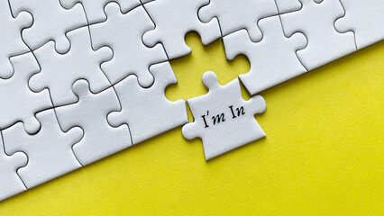 Fototapeta premium Top view of text - I am in. On yellow background of white jigsaw missing pieces. Conceptual