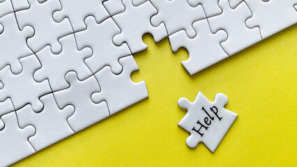 Obraz premium Help word on a jigsaw puzzle with yellow background.