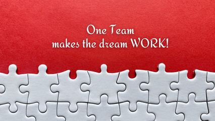 Top view of business quote - One team makes the dream work. With red cover and jigsaw puzzle...