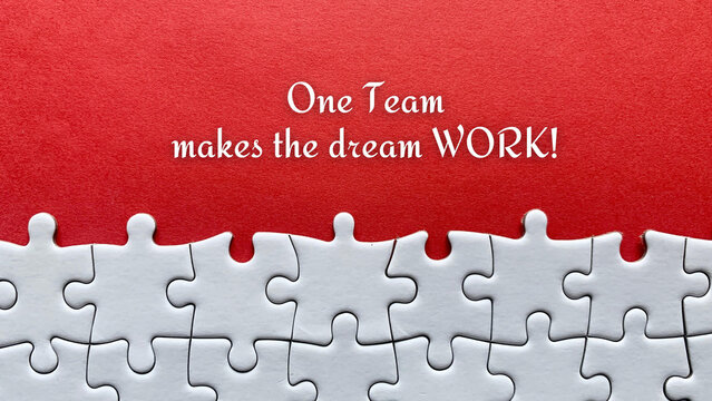 Top view of business quote - One team makes the dream work. With red cover and jigsaw puzzle background.