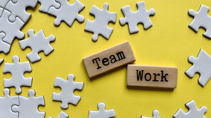 Obraz premium Wooden blocks with words - Team work. Jigsaw puzzle and yellow desk background.