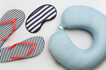 Flip-flops, sleeping mask and neck pillow on white background, closeup