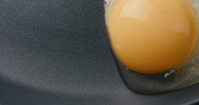 Egg pour frying pan sunny side up cooking top down in macro close up
