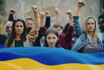Crowd of activists protesting against Russian military invasion in Ukraine walking in street.