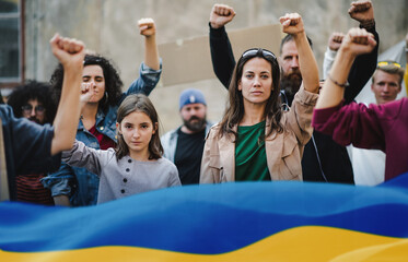 Crowd of activists protesting against Russian military invasion in Ukraine walking in street.