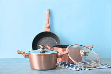 Set of copper kitchen utensils on table against blue background