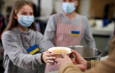 Volunteers serving hot soup for Ukrainian migrants in refugee centre, Russian conflict concept.