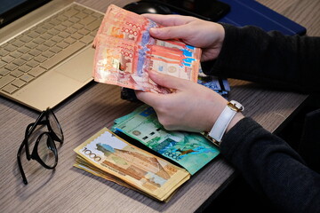 Almaty, Kazakhstan - 12.01.2020 : Recalculation of banknotes of different denominations in the hands. Kazakhstan's currency is tenge.